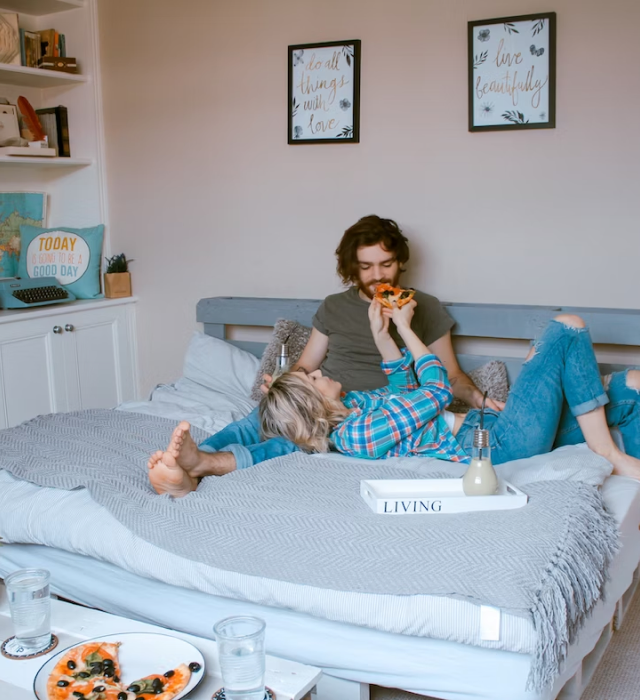 Hip couple in bed, eating pizza